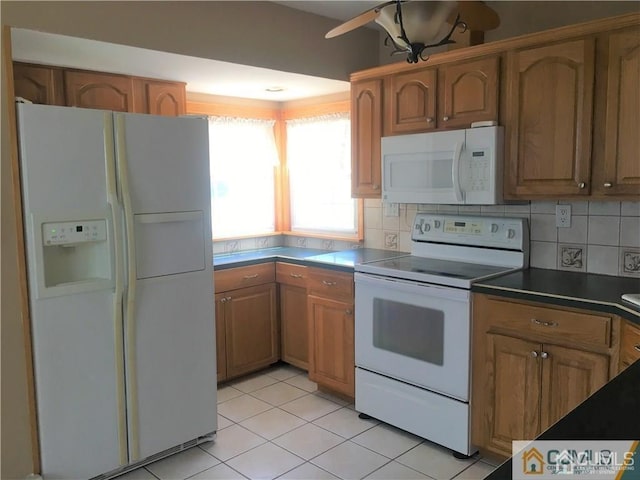 kitchen featuring light tile patterned floors, tasteful backsplash, dark countertops, ceiling fan, and white appliances