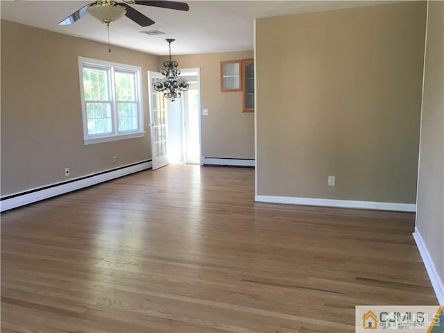 spare room featuring ceiling fan with notable chandelier, baseboards, baseboard heating, and wood finished floors