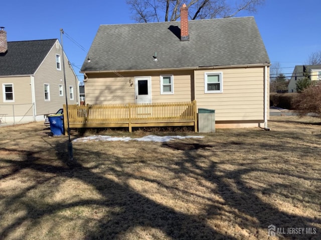 rear view of property with a deck, a shingled roof, and a chimney