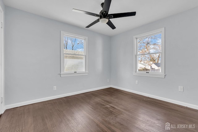 empty room featuring a ceiling fan, baseboards, and dark wood-style flooring