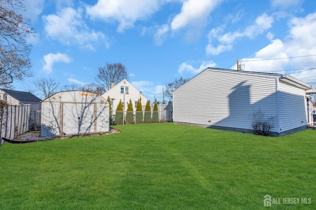 view of yard with a storage shed, a fenced backyard, and an outbuilding