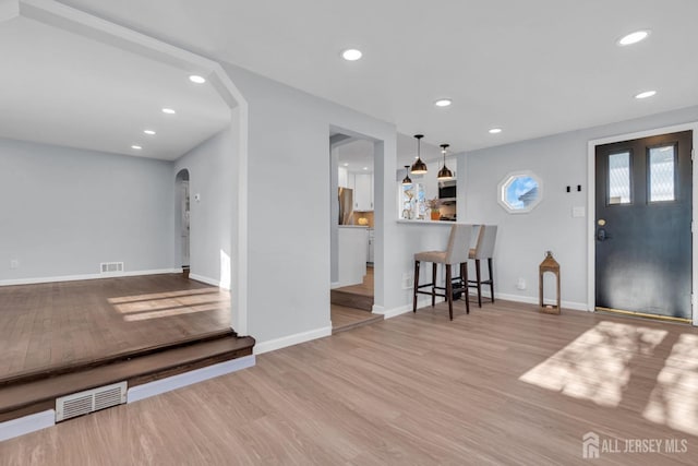 foyer entrance with visible vents, arched walkways, wood finished floors, and recessed lighting