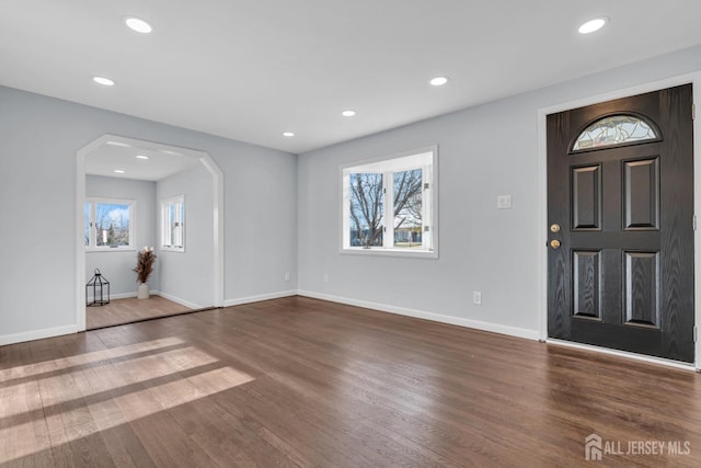 foyer entrance featuring arched walkways, baseboards, recessed lighting, and wood finished floors