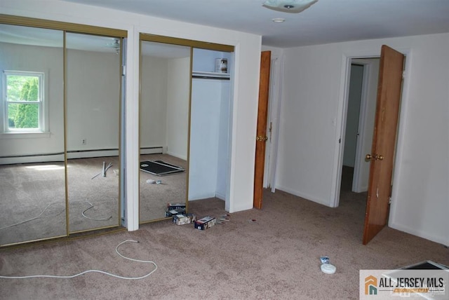 unfurnished bedroom with carpet, two closets, and a baseboard heating unit
