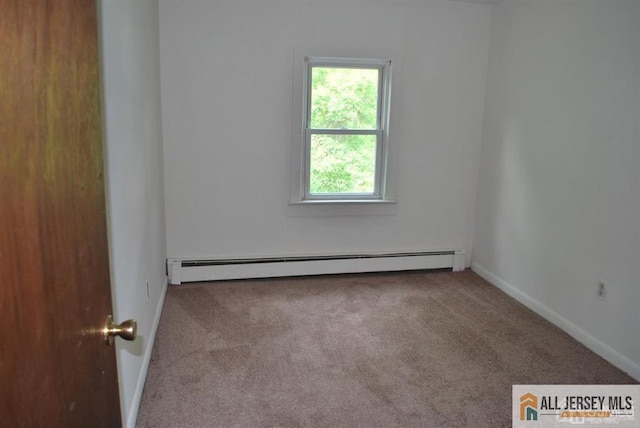 spare room with carpet flooring, baseboards, and a baseboard heating unit