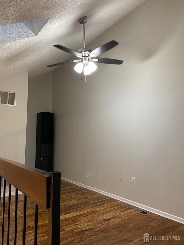 unfurnished room with lofted ceiling, ceiling fan, dark hardwood / wood-style floors, and a textured ceiling