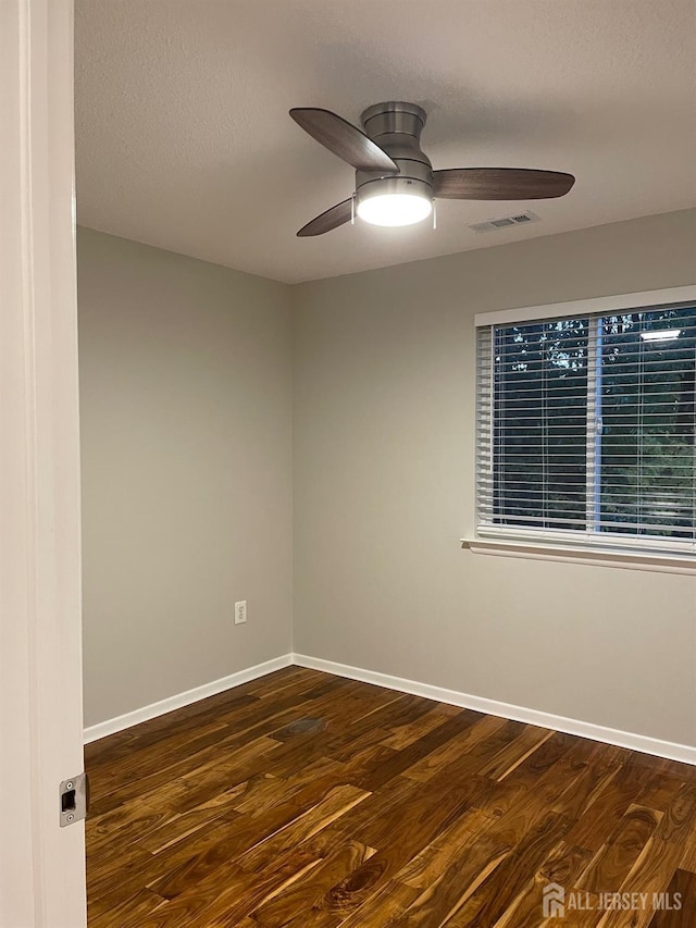 unfurnished room with a textured ceiling, ceiling fan, and dark hardwood / wood-style flooring