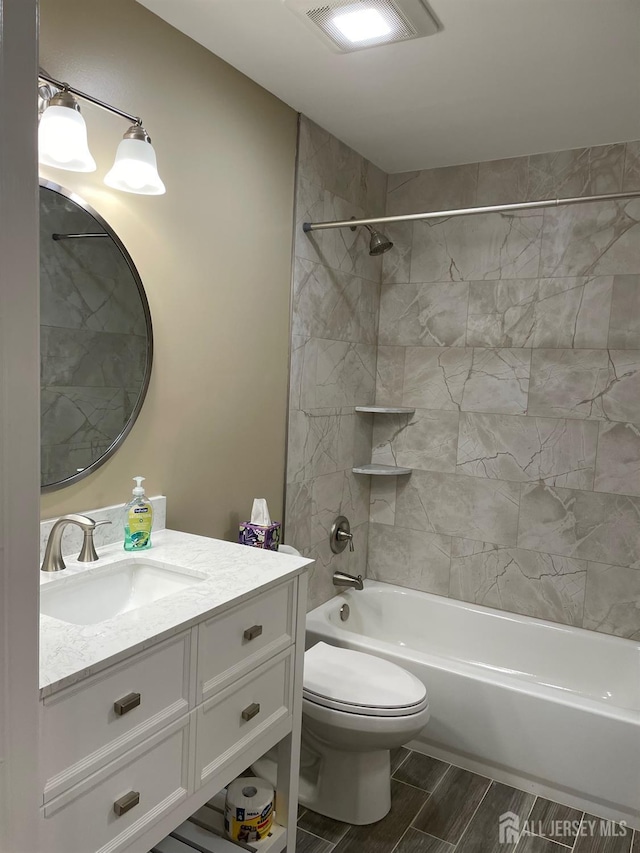 full bathroom featuring toilet, tiled shower / bath, and vanity