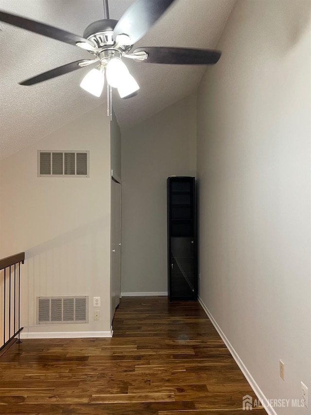 empty room with vaulted ceiling, ceiling fan, dark hardwood / wood-style flooring, and a textured ceiling