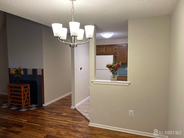 unfurnished dining area with dark hardwood / wood-style flooring, an inviting chandelier, and a textured ceiling