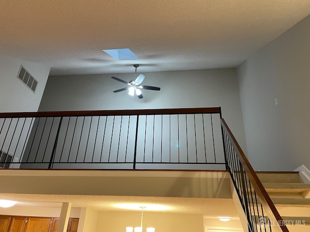 stairway featuring a textured ceiling, ceiling fan, and a skylight