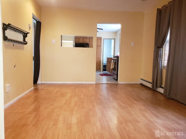 empty room with baseboards, light wood-type flooring, and a baseboard radiator