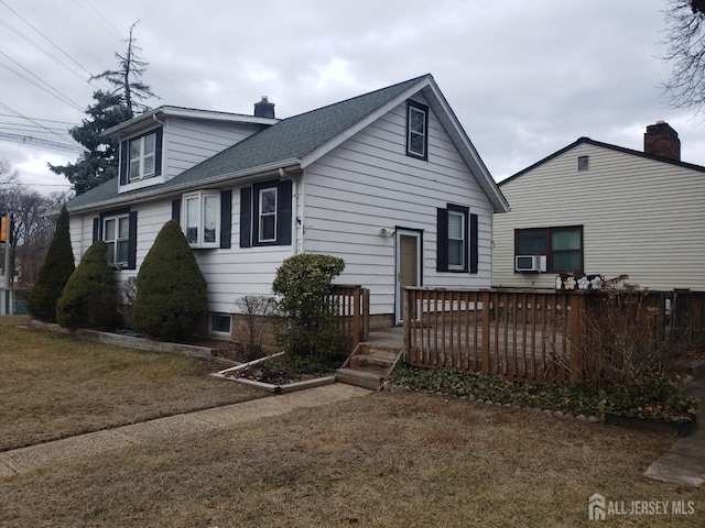 view of front of home featuring a wooden deck, cooling unit, a chimney, and a shingled roof