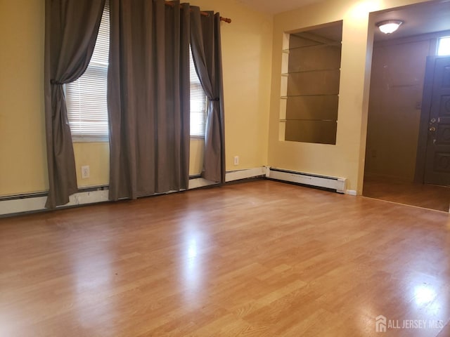 empty room with a baseboard heating unit and wood finished floors