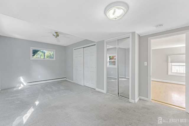 unfurnished bedroom with ceiling fan, baseboard heating, light carpet, and multiple closets