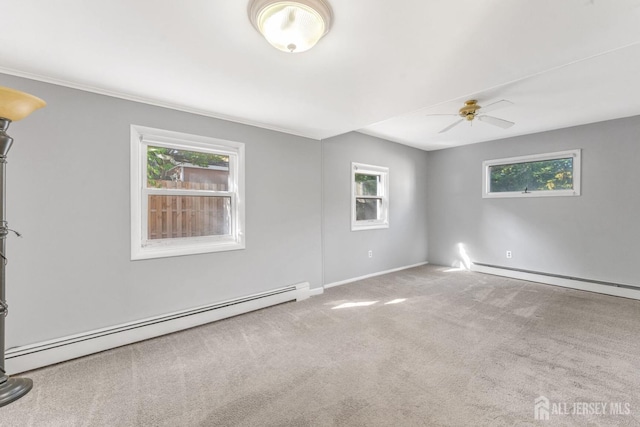 spare room featuring baseboard heating, a wealth of natural light, and light carpet