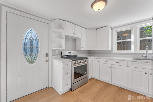 kitchen with white cabinets, light hardwood / wood-style floors, and stainless steel gas stove