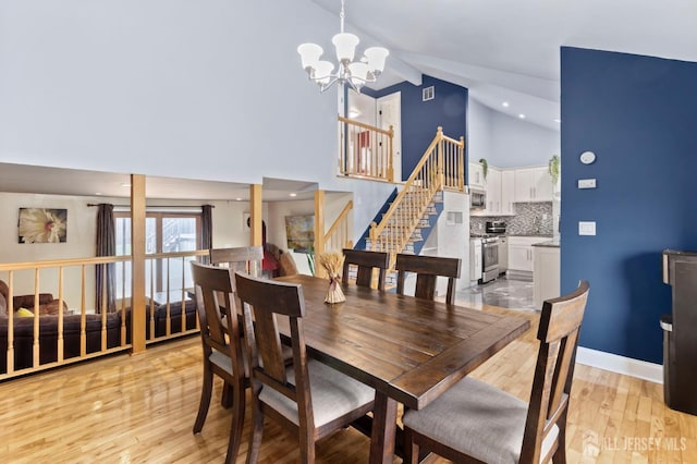 dining room featuring high vaulted ceiling, a chandelier, stairs, light wood finished floors, and beam ceiling