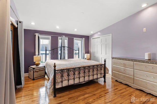 bedroom with wood finished floors, access to exterior, vaulted ceiling, recessed lighting, and a closet