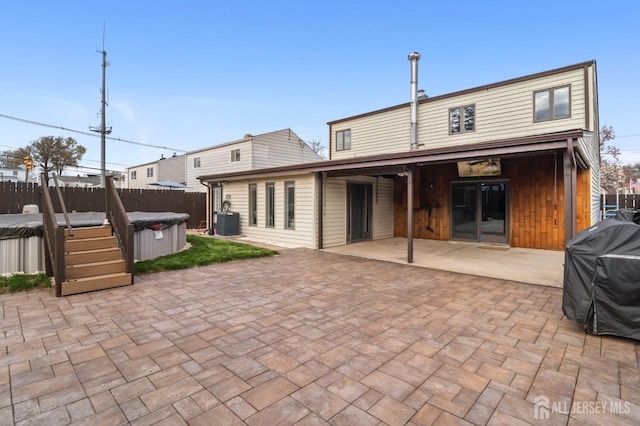 rear view of house with a hot tub, fence, a patio area, and central air condition unit