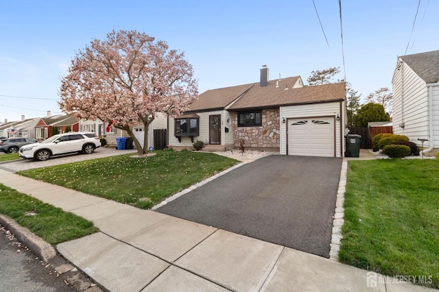 ranch-style house featuring an attached garage, asphalt driveway, a front lawn, a chimney, and stone siding