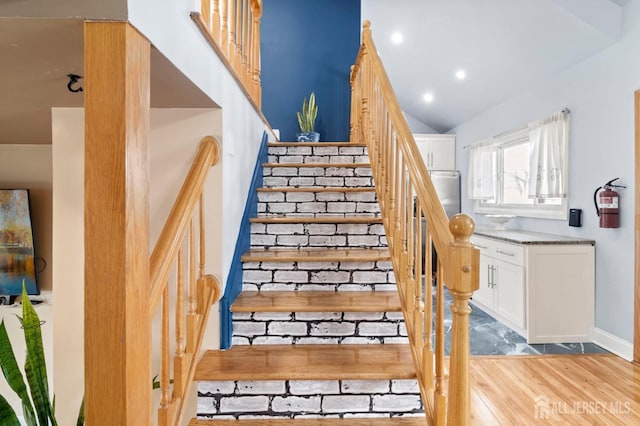 stairs featuring wood finished floors, baseboards, vaulted ceiling, and recessed lighting