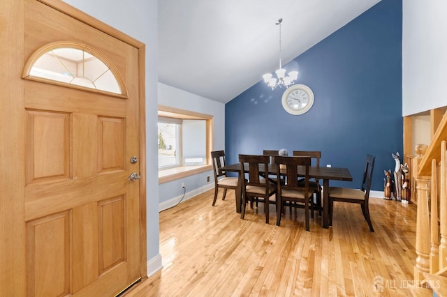 dining room featuring high vaulted ceiling, light wood finished floors, a chandelier, and baseboards