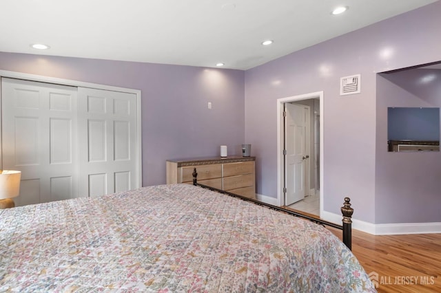 bedroom with a closet, baseboards, wood finished floors, and recessed lighting