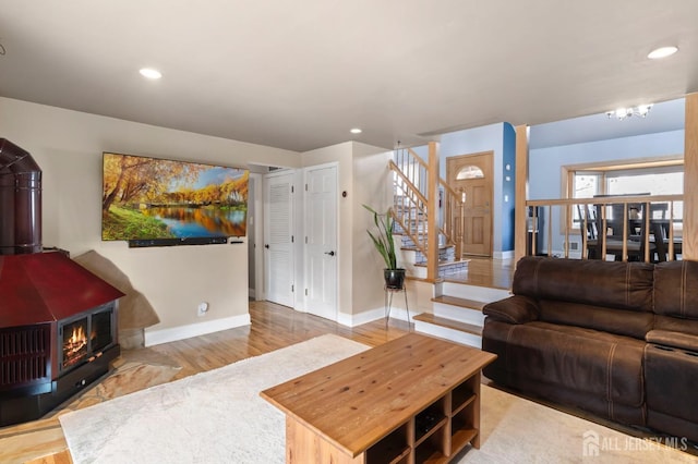 living area with stairway, baseboards, recessed lighting, a wood stove, and wood finished floors