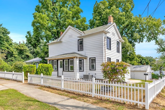 view of front of house with a chimney, central air condition unit, and a fenced front yard