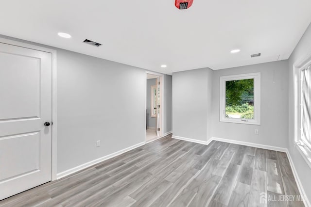 spare room featuring wood finished floors, baseboards, and recessed lighting