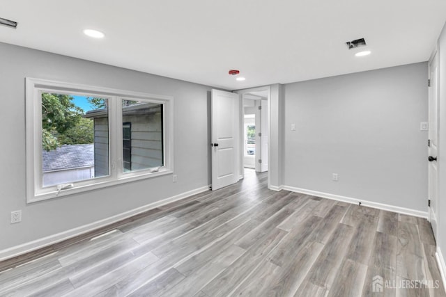 unfurnished room with recessed lighting, light wood finished floors, and baseboards