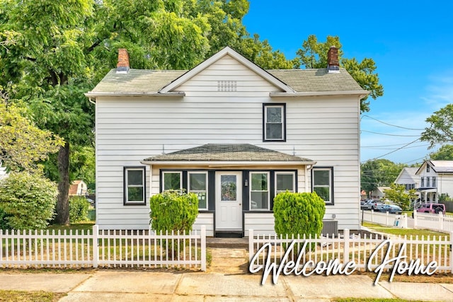 traditional-style house with a chimney, a fenced front yard, roof with shingles, and central air condition unit