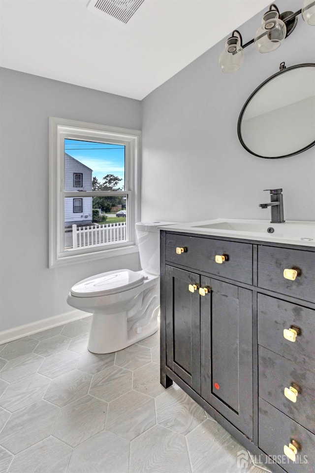 bathroom featuring toilet, vanity, and baseboards
