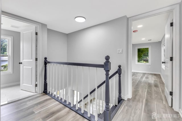 hallway featuring an upstairs landing, wood finished floors, and baseboards