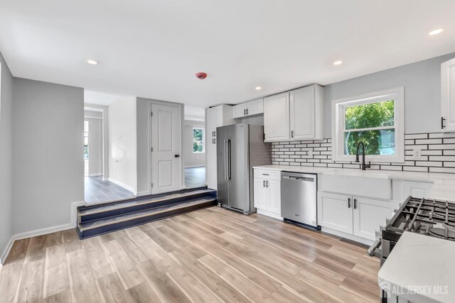 kitchen with stainless steel appliances, light countertops, backsplash, healthy amount of natural light, and recessed lighting