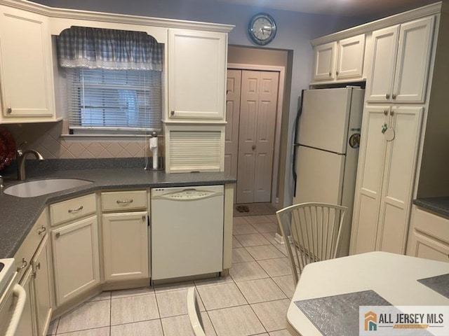 100 Neilly Ct Unit 100, Old Bridge, NJ 08857 - kitchen with white appliances, a sink, light tile patterned floors, dark countertops, and backsplash