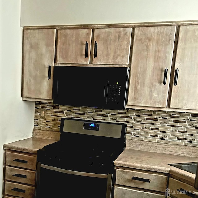 kitchen with stainless steel stove, light countertops, backsplash, and black microwave