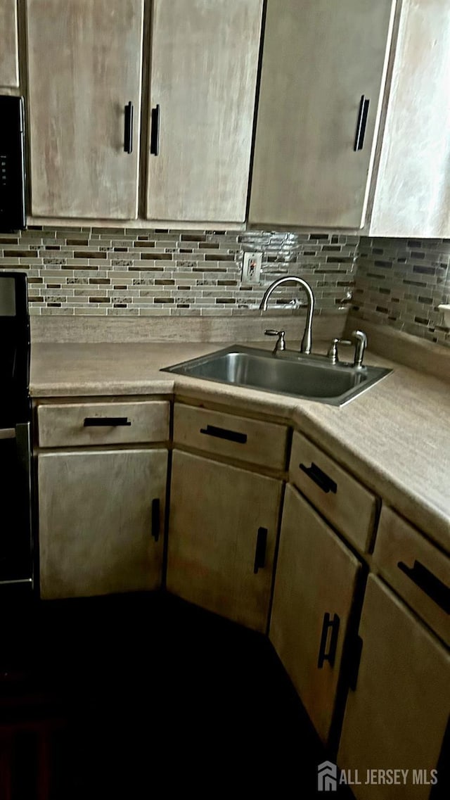 kitchen with tasteful backsplash, light countertops, and a sink