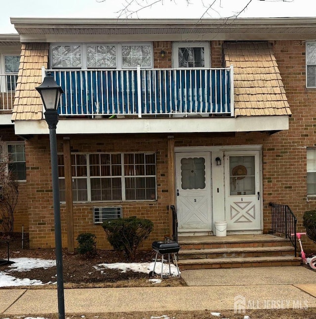view of property featuring a balcony and brick siding