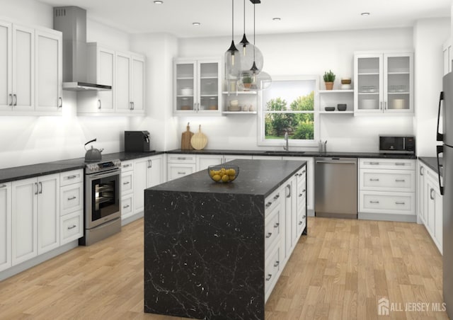 kitchen with pendant lighting, wall chimney range hood, light hardwood / wood-style flooring, stainless steel appliances, and a center island