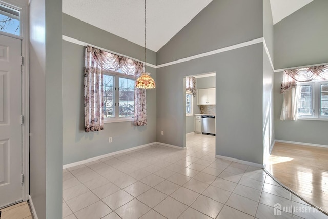 unfurnished dining area with light tile patterned floors, high vaulted ceiling, baseboards, and a healthy amount of sunlight