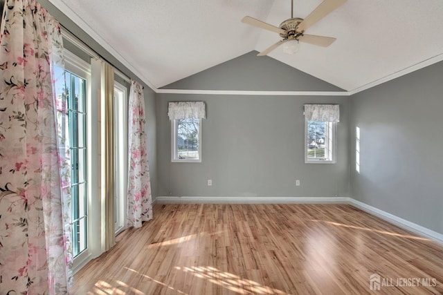 spare room with light wood-style floors, baseboards, vaulted ceiling, and a wealth of natural light