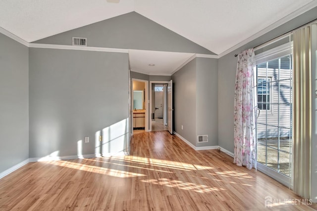 spare room with lofted ceiling, light wood finished floors, baseboards, and visible vents