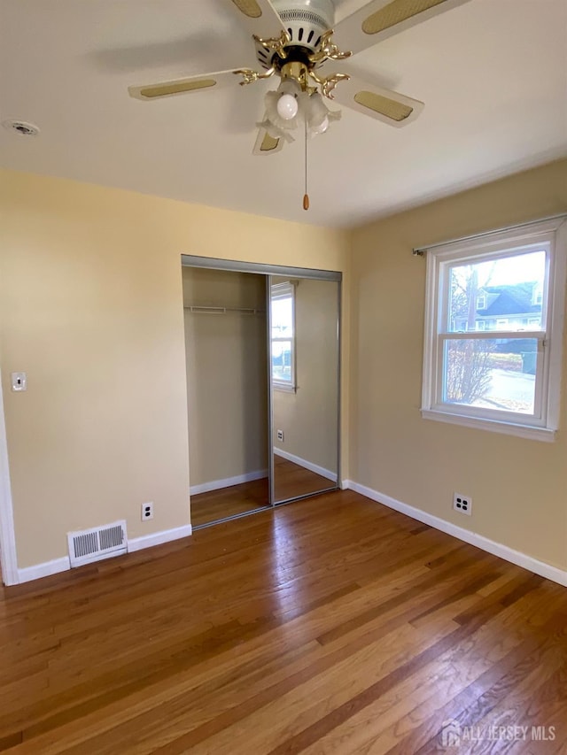 unfurnished bedroom with hardwood / wood-style floors, ceiling fan, and a closet