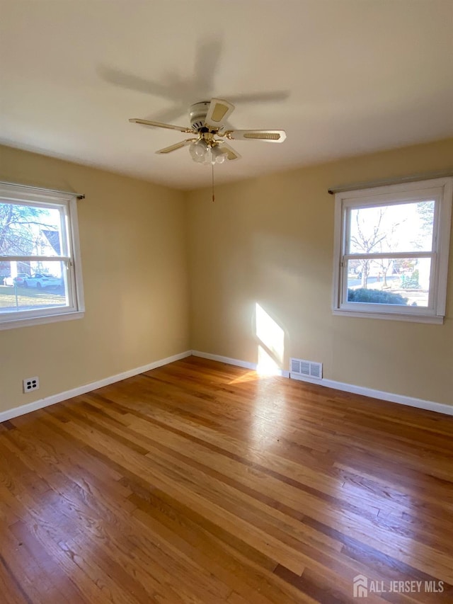 spare room featuring ceiling fan, plenty of natural light, and hardwood / wood-style floors