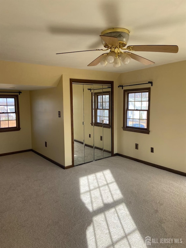 unfurnished bedroom featuring multiple windows, light carpet, a closet, and ceiling fan