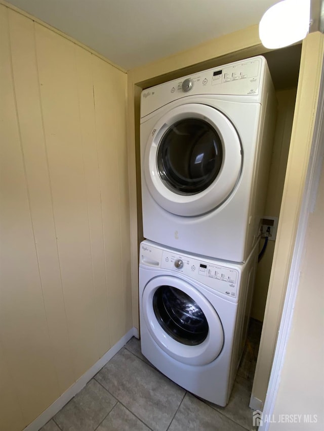 laundry room with tile patterned floors and stacked washing maching and dryer