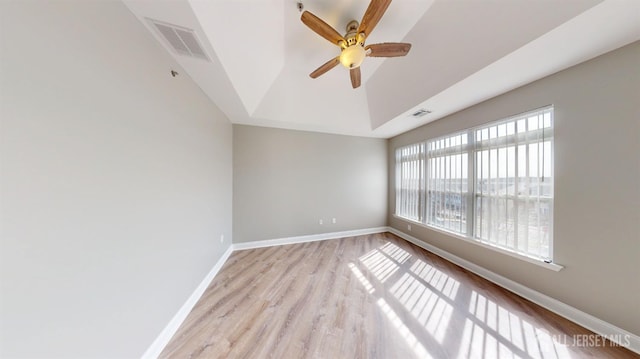 spare room with visible vents, a raised ceiling, light wood-type flooring, and baseboards