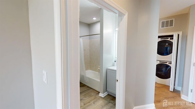 interior space with wood finished floors, visible vents, baseboards, shower / bath combo, and stacked washer and clothes dryer